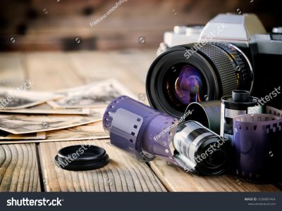 stock-photo-close-up-of-mm-films-vintage-photographic-prints-camera-film-and-on-a-rustic-wooden-table-1028681464