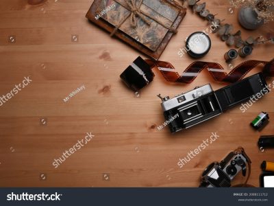 stock-photo-top-view-film-rolls-retro-camera-and-book-on-wooden-table-2088111712